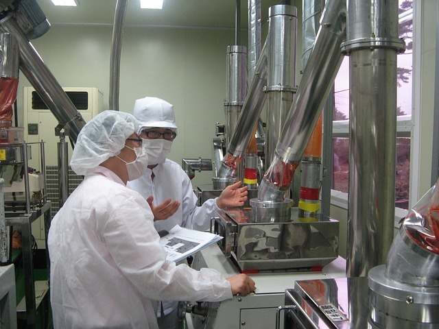 食品工場の製造ラインで防塵衣を着て設備を確認する従業員